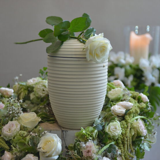 Weiße Urne dekoriert mit einem Urnenkranz aus weißen und rosa Rosen