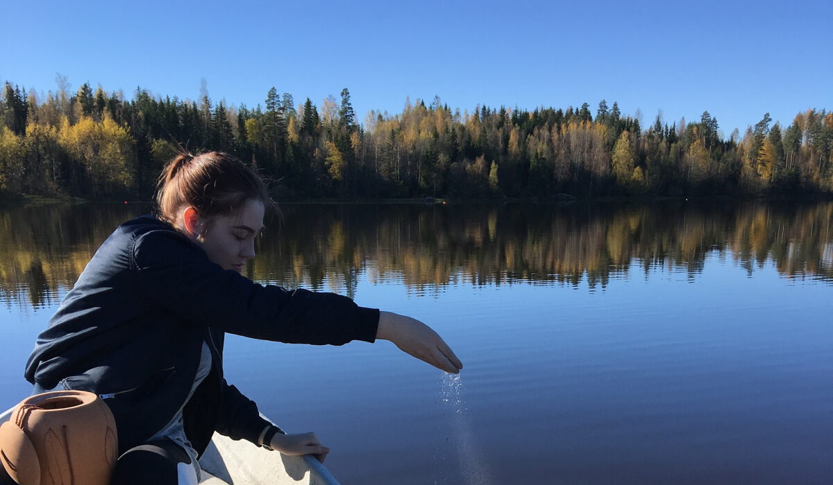 Eine Frau streut Asche in einen See